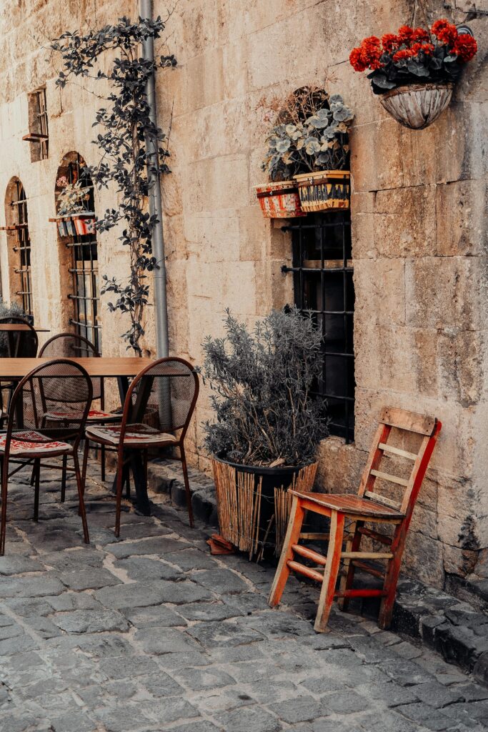 Quaint street scene highlighting rustic charm with vintage chairs, tables, and floral decor.